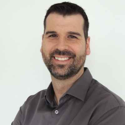 Homme souriant à la barbe brune en chemise grise